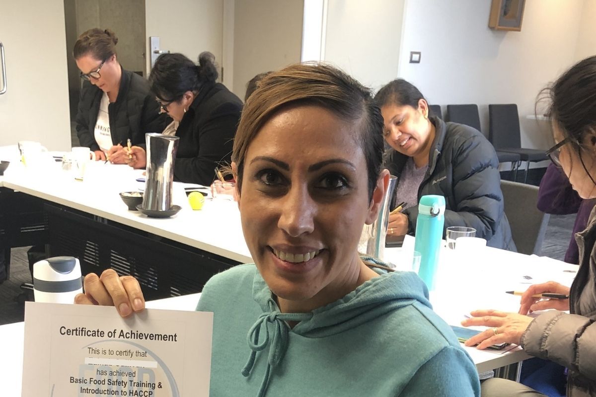 A trainee holding her Food Safety Certification after completing Food Safe's basic food safety and hygiene certificate training course.