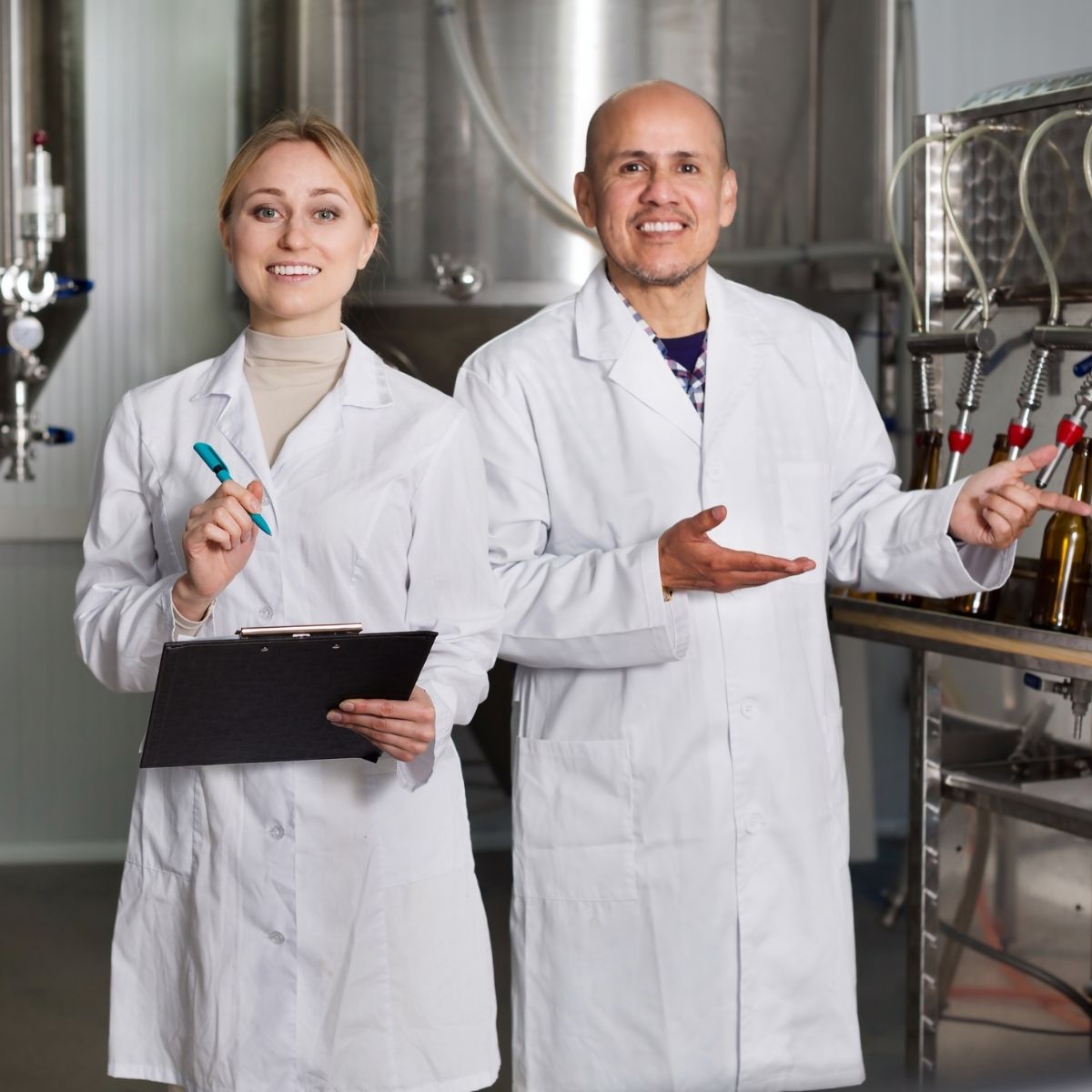 Two internal auditors standing in a food process area with clipboards, training in internal auditing.