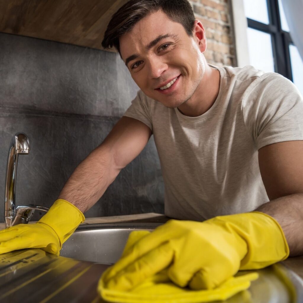 A food handler using a kitchen cleaning checklist to clean